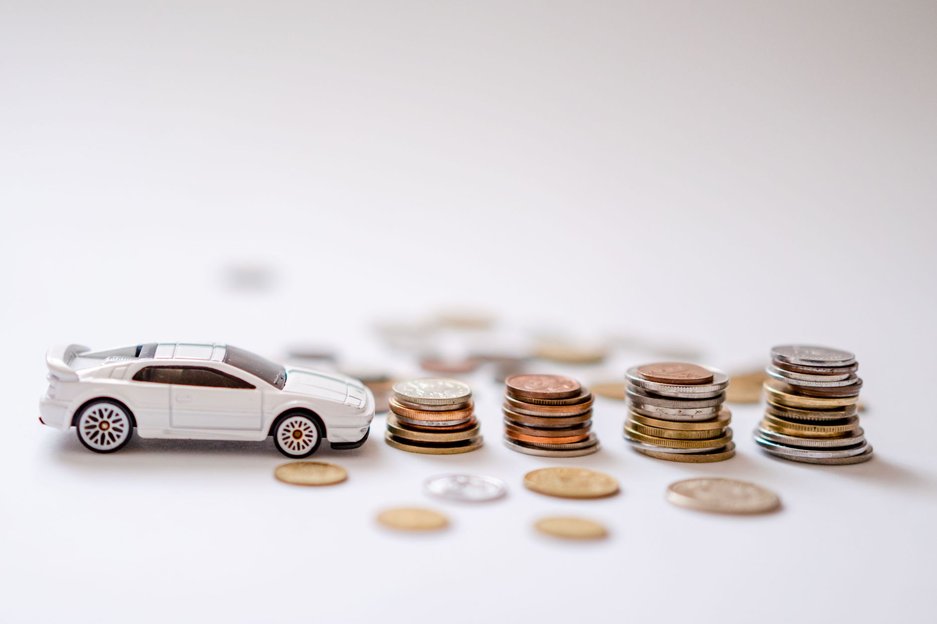 Carrinho de brinquedo branco ao lado de pilhas de moedas